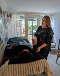 Kath Whitehorn performing muscle monitoring during a kinesiology session with a client at Hill Tribe Healing.