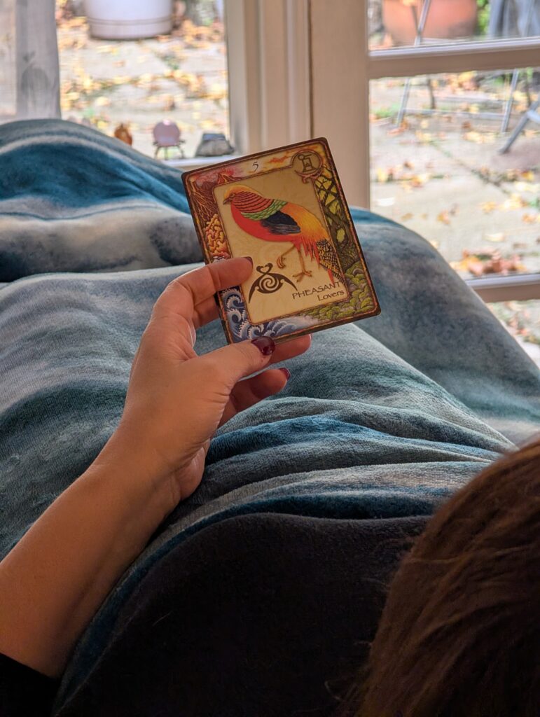 Client holding an oracle card during a one on one session at Hill Tribe Healing, while resting comfortably on a treatment table.